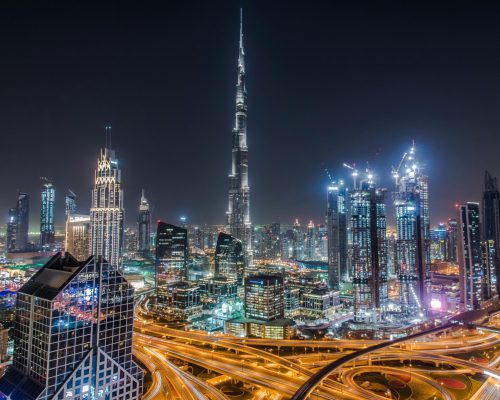A stunning view of Dubai's illuminated skyline featuring the towering Burj Khalifa at night.